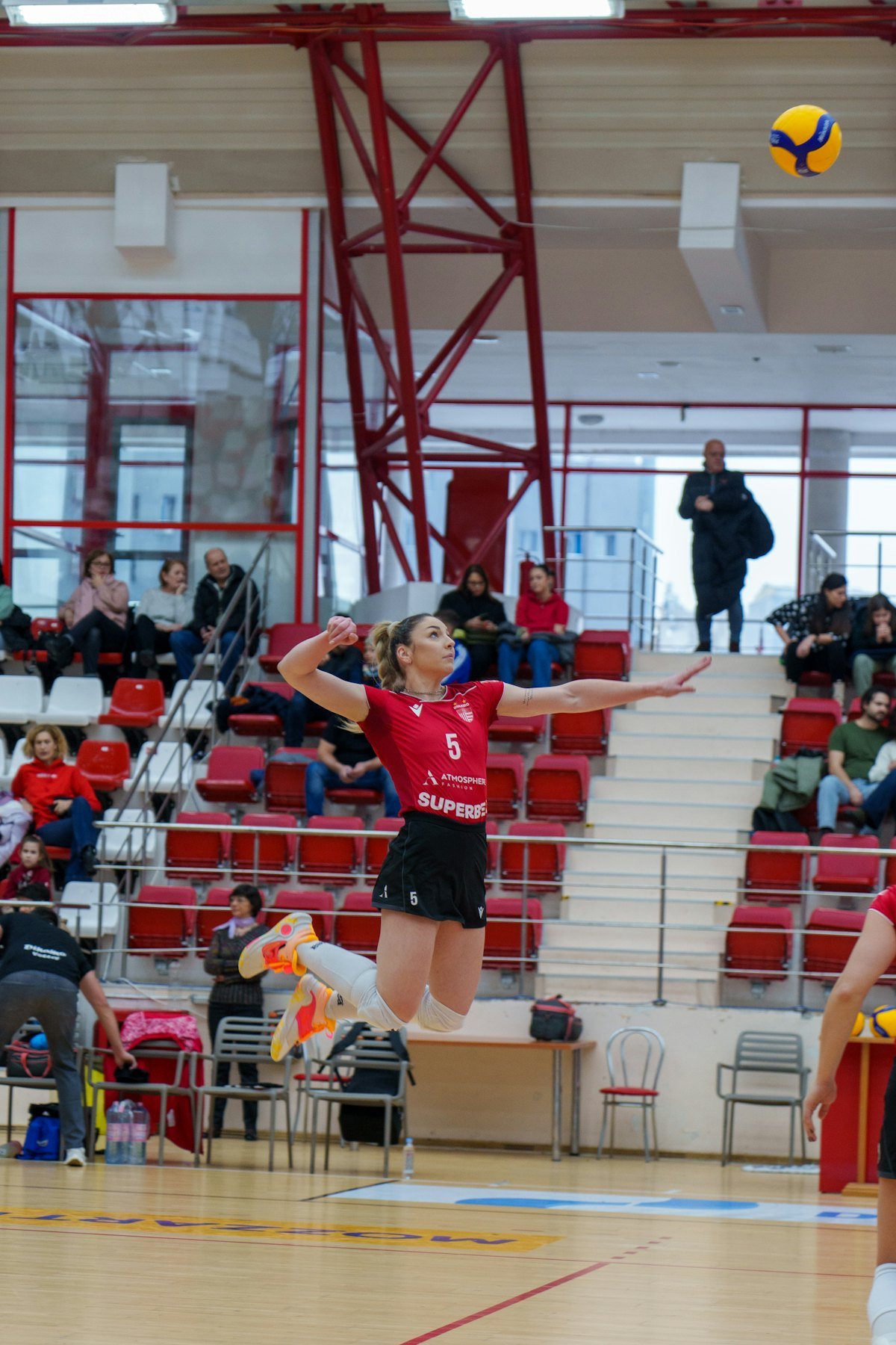 A player in a red jersey jumps for the ball in a school gym