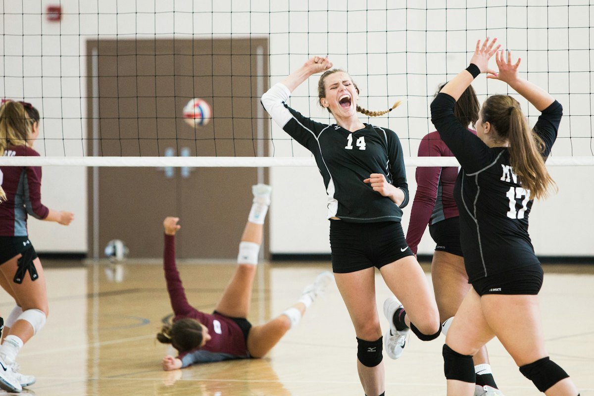 Two players go up at the net during an indoor women's match