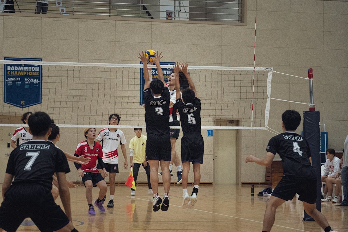Players jump at the net to block during an indoor match