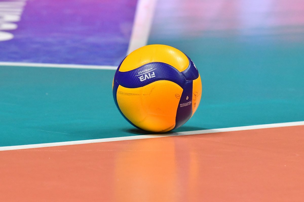 A volleyball resting on the painted floor of an indoor court